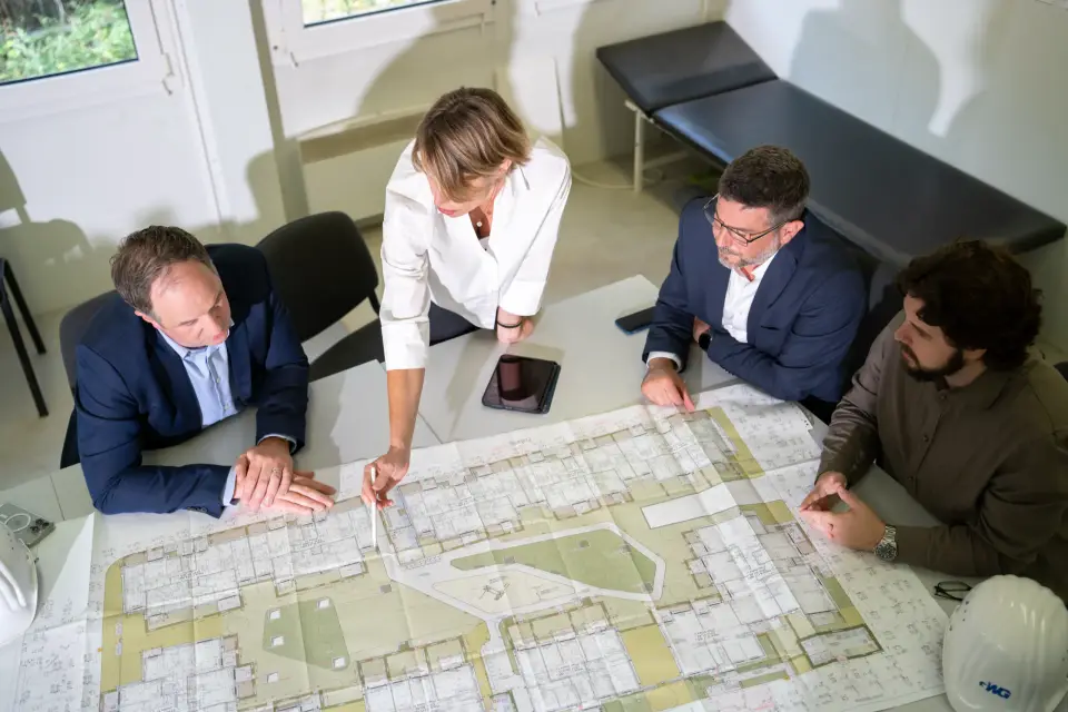 Geschäftsführung, Projektleitung und Planer der GWG Rhein-Erft besprechen im Baucontainer den Lageplan eines Neubauquartiers im Rhein-Erft-Kreis.
