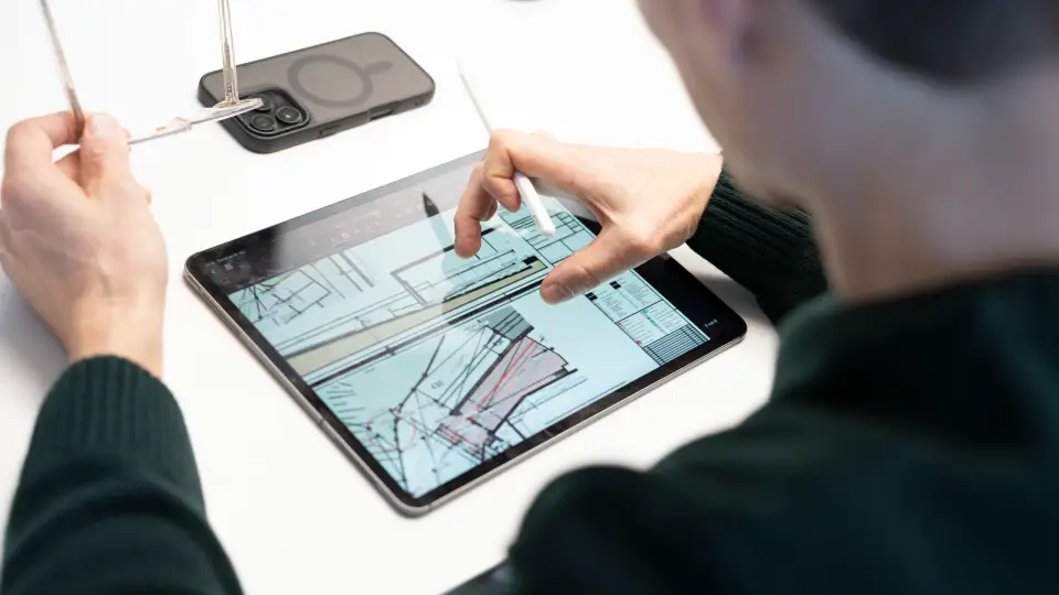 Ein Architekt skizziert mit dem Stift auf einem Tablet an einem Grundriss