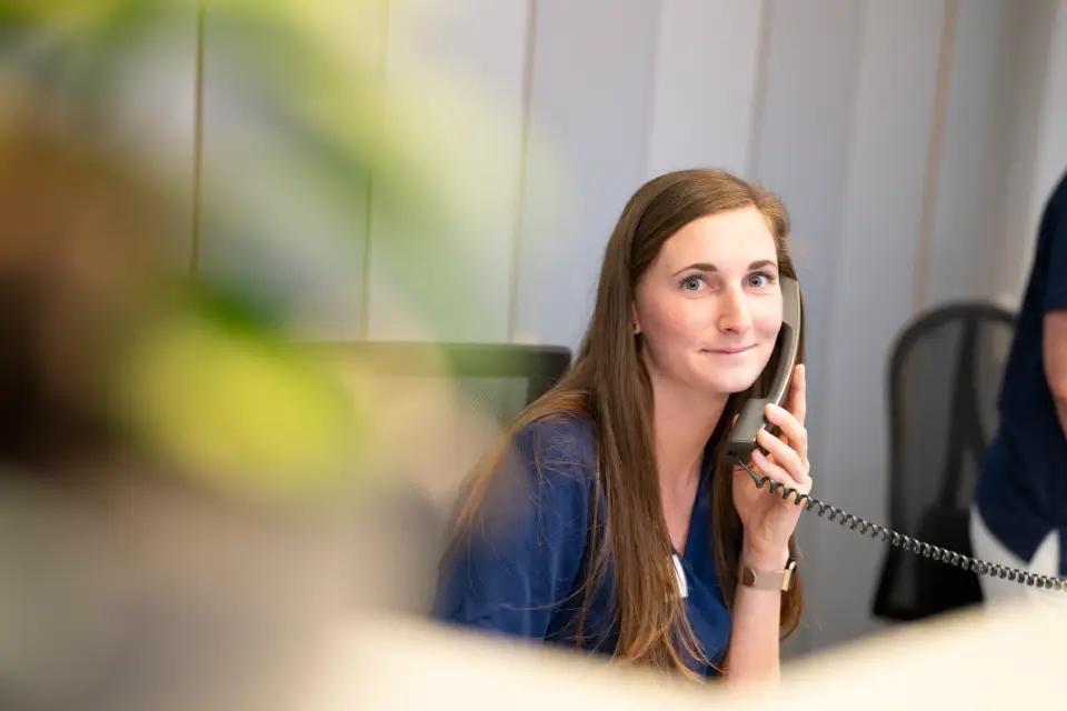 Lächelnde Mitarbeiterin telefoniert am Empfang der Pan Klinik in Köln