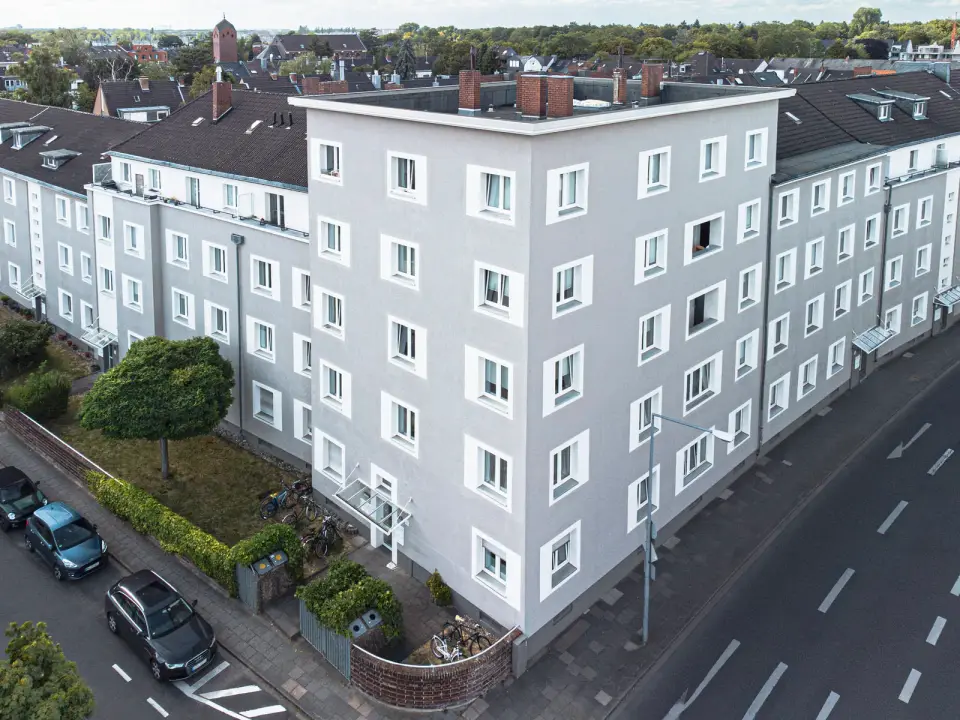 Frisch gestrichene Fassade eines Eckhauses der GWG zu Köln an einer Straßenkreuzung, aus erhöhter Perspektive fotografiert.