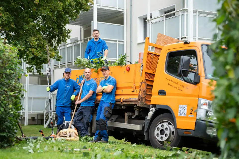 Gärtnerteam der GWG Rhein-Erft vor einem Wohnquartier