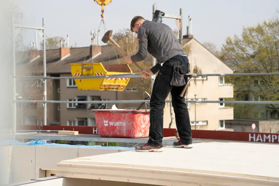 Handwerker montiert auf dem Dach des Holzbaus Woodstöckchen der Aachener SWG in Köln-Bilderstöckchen ein Holzelement