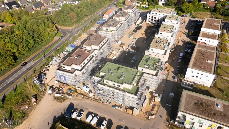 Luftbild eines Neubauquartiers der GWG Rhein-Erft im Bau mit eingerüsteten Mehrfamilienhäusern und begrünten Dächern im Rhein-Erft-Kreis.