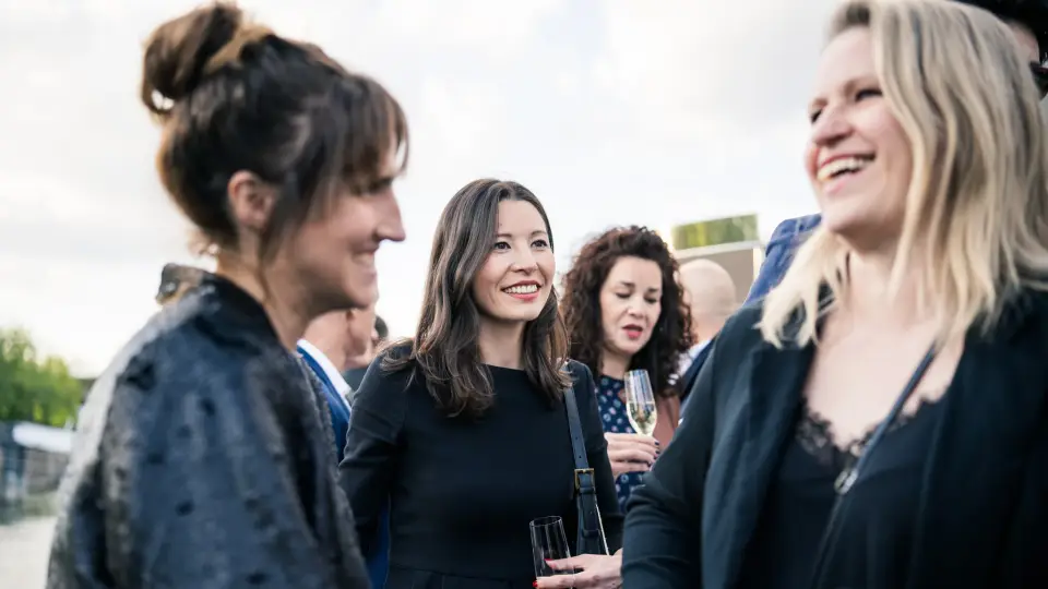 Gäste des GSK Stockmann Lawyers Summit lachen beim Netzwerken an Deck eines Schiffs auf dem Rhein in Köln