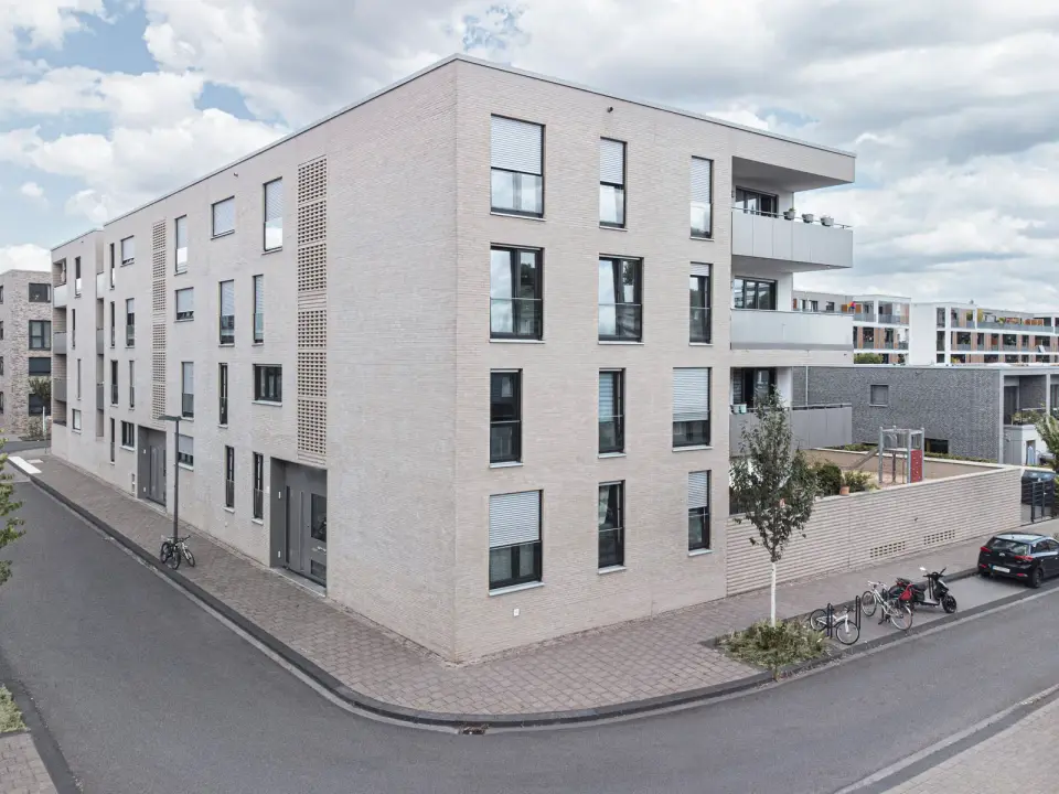 Neubau der GWG zu Köln mit hellem Klinker und Balkonen an einer Straßenecke in Köln.