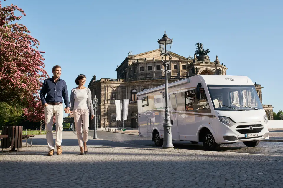 Ein Paar spaziert vor dem integrierten Carado Wohnmobil I338 an der Semperoper in Dresden