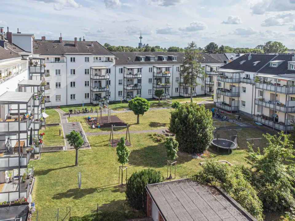 Erhöhter Blick auf eine Siedlung der GWG zu Köln mit Balkonen, Bäumen und großem grünen Innenhof in Köln.