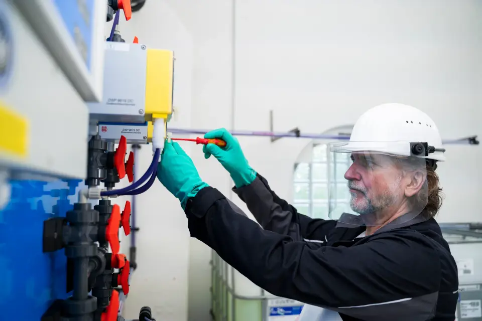 Techniker von LEDOS mit Helm und Schutzhandschuhen arbeitet an einer Anlage zur Wasseraufbereitung