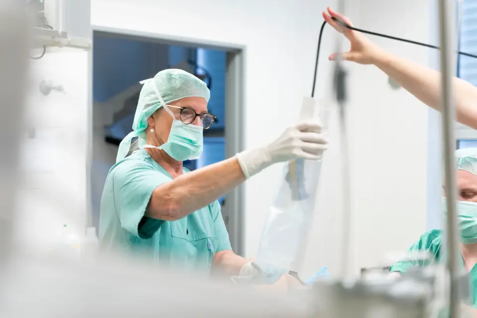 Pflegekraft mit Haube und Mundschutz bereitet im Operationssaal der Pan Klinik in Köln eine Infusion vor